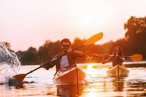 kajakken is hun leven. vrolijk jong paar kajakken Aan rivier- samen met zonsondergang in de achtergronden foto