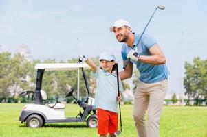 kijken Bij dat vrolijk jong Mens omarmen zijn zoon en op zoek weg terwijl staand Aan de golf Cursus foto