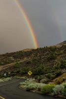 bochtige weg met een dubbele regenboog eroverheen foto