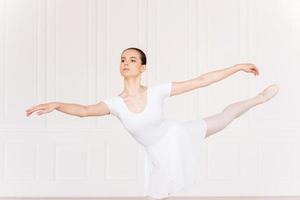 genade en schoonheid in haar beweegt. mooi jong ballerina in wit tutu dansen in ballet studio foto