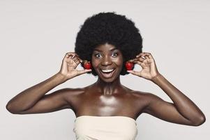 portret van mooi jong Afrikaanse vrouw Holding aardbei Leuk vinden oorbellen en glimlachen foto