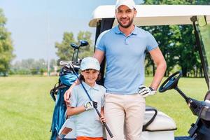 wij liefde golf glimlachen jong Mens omarmen zijn zoon terwijl leunend golf kar foto