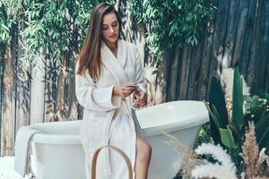 mooi jong vrouw hydraterend hand- room terwijl leunend Bij de bad buitenshuis foto