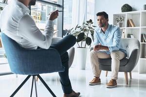 sharing zijn problemen. jong gefrustreerd Mens oplossen zijn mentaal problemen terwijl hebben behandeling sessie met psycholoog foto