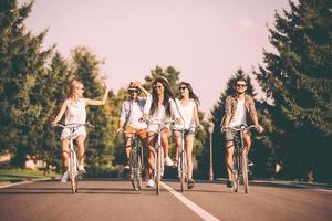 ze liefde uitgeven tijd samen. groep van jong mensen rijden fietsen langs een weg en op zoek gelukkig foto