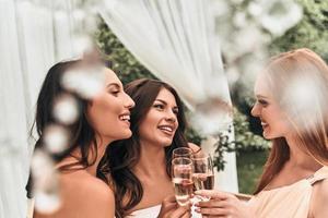 het beste vrienden zijn altijd in de omgeving van. aantrekkelijk jong bruid roosteren met Champagne met haar mooi bruidsmeisjes terwijl staand buitenshuis samen foto