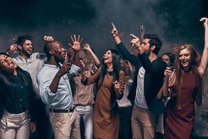 genieten van verbazingwekkend feest. groep van mooi jong mensen dansen met Champagne fluiten en op zoek gelukkig foto