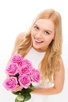 schoonheid met rozen. top visie van mooi jong blond haar- vrouw Holding boeket met roze rozen en glimlachen terwijl staand geïsoleerd Aan wit foto