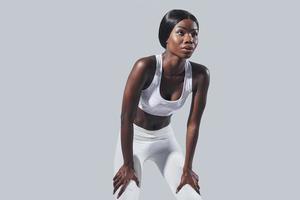 zelfverzekerd jong Afrikaanse vrouw in sport- kleding staand tegen grijs achtergrond foto