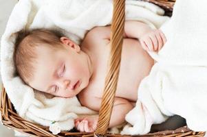 slapen in een mand. top visie van weinig baby slapen terwijl aan het liegen in rieten mand en gedekt met handdoek foto