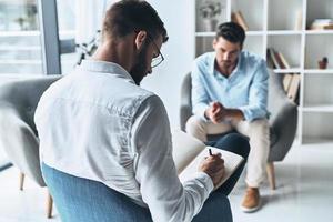 geconfronteerd sociaal moeilijkheden. jong gefrustreerd Mens oplossen zijn mentaal problemen terwijl hebben behandeling sessie met psycholoog foto