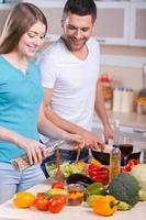 paar Koken diner. gelukkig jong paar Koken avondeten in de keuken foto