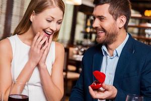 zullen u trouwen me knap jong Mens maken een voorstel terwijl geven een verloving ring naar zijn vriendin in restaurant foto