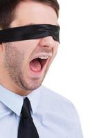 Blind beheer. jong zakenman in blinddoek geschreeuw terwijl staand geïsoleerd Aan wit foto