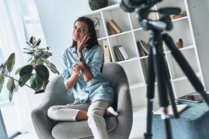 testen schoonheid Product. aantrekkelijk jong vrouw toepassen nieuw schoonheidsmiddelen terwijl maken nieuw video binnenshuis foto