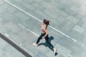 top visie van aantrekkelijk jong vrouw in sport- kleding rennen buitenshuis foto