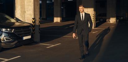 vol lengte van zelfverzekerd volwassen Mens in vol pak wandelen door parkeren veel foto