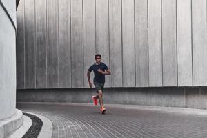 ochtend- training. vol lengte van jong Mens in sport- kleding rennen terwijl oefenen buiten foto