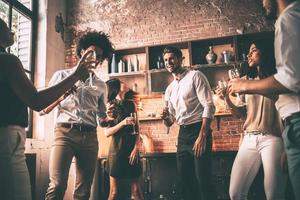 ze liefde dansen. laag hoek visie van vrolijk jong mensen dansen en drinken terwijl genieten van huis partij Aan de keuken foto