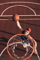 het beste basketbal speler. top visie van jong Mens in sport- kleding scoren een dichtslaan dunk terwijl spelen basketbal buitenshuis foto