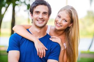 gelukkig naar worden samen. portret van mooi jong liefhebbend paar glimlachen en op zoek Bij camera terwijl staand buitenshuis foto