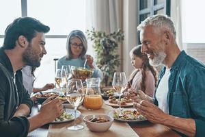 gelukkig meerdere generaties familie communiceren en glimlachen terwijl hebben avondeten samen foto