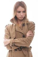 herfst stijl. aantrekkelijk jong vrouw in jas op zoek weg terwijl staand tegen wit achtergrond foto