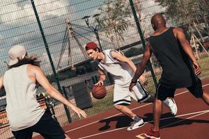 vol van energie. groep van jong mannen in sport- kleding spelen basketbal terwijl uitgeven tijd buitenshuis foto