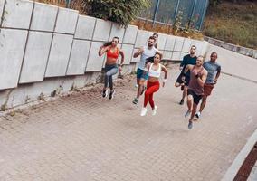 vol lengte top visie van jong mensen in sport- kleding jogging terwijl oefenen buitenshuis foto
