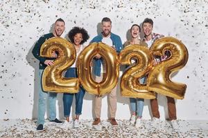 groep van jong mooi mensen in gewoontjes kleding draag- goud gekleurde getallen en glimlachen foto