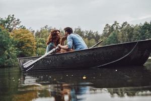 genieten van elke minuut samen. mooi jong paar zoenen terwijl roeien een boot foto