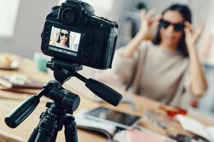 mooi jong vrouw in gewoontjes kleding tonen eyewear terwijl maken sociaal media video foto