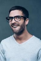 Leuk vinden een nerd. jong nerd Mens in bril maken een gezicht terwijl staand tegen grijs achtergrond foto
