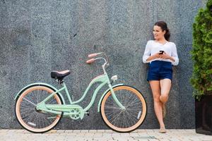 jong en stijlvol. mooi jong glimlachen vrouw staand in de buurt haar wijnoogst fiets Aan de straat foto