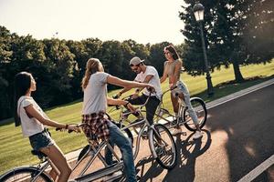 Super goed dag voor een fiets rijden. groep van jong modern mensen in gewoontjes slijtage wielersport terwijl uitgeven zorgeloos tijd buitenshuis foto