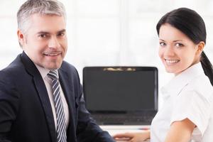 werken samen. vrolijk Mens en vrouw in formele kleding werken Aan laptop en op zoek over- schouder foto