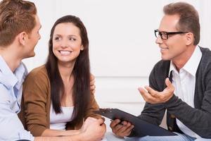 gevoel gelukkig nu. gelukkig jong paar op zoek Bij elk andere terwijl psychiater met klembord gebaren en glimlachen foto