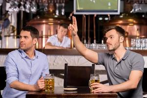 ober twee jong mannen zittend in bar terwijl een van hen roeping een ober foto