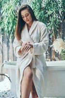 mooi jong vrouw hydraterend hand- room terwijl leunend Bij de bad buitenshuis foto