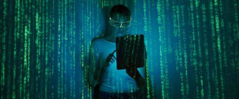 zelfverzekerd vrouw in futuristische bril gebruik makend van digitaal tablet tegen donker achtergrond met groen symbolen foto