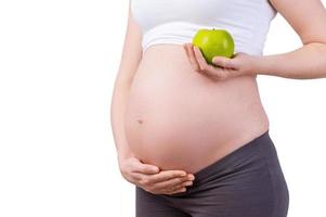 enkel en alleen gezond voedsel. bijgesneden beeld van zwanger vrouw Holding groen appel terwijl staand geïsoleerd Aan wit foto
