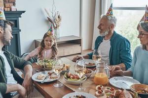 gelukkig familie vieren verjaardag van weinig meisje terwijl zittend Bij de dining tafel Bij huis foto