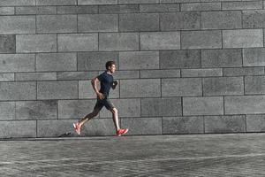 sneller dan ooit. vol lengte van jong Mens in sport- kleding rennen terwijl oefenen buiten foto