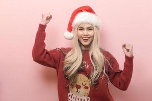 portret van gelukkig Kaukasisch jong vrouw in de kerstman claus hoed over- roze achtergrond foto