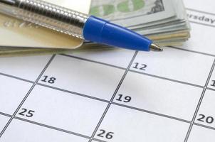 pen en credit kaart Aan veel honderd ons dollar rekeningen Aan kalender bladzijde dichtbij omhoog foto