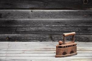 de zwaar en roestig oud steenkool ijzer leugens Aan een houten oppervlakte foto