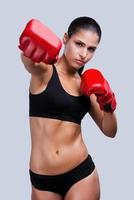 vrouw boksen. mooi jong sportief vrouw boksen terwijl staand tegen grijs achtergrond foto