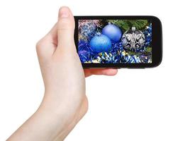 hand- houdt mobiele telefoon met Kerstmis decoraties foto