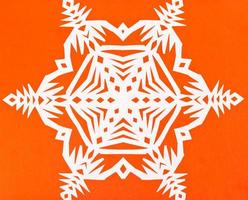 wit sneeuwvlok Aan oranje papier foto