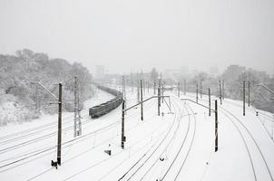 een lang trein van vracht auto's is in beweging langs de spoorweg spoor. spoorweg landschap in winter na sneeuwval foto